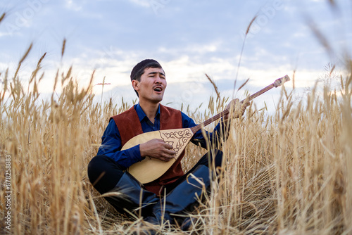 Kazakh, a man in Kazakh national dress playing dombra in the steppe. Kazakhstan. Central Asia. Nomads. | Казах, мужчина в казахской национальной одежде играет на домбре в степи. Казахстан.Средняя Азия