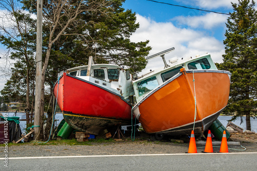 Commercial inshore fishing boats parked and propped up on land by the side of the road on St Margaret’s Bay in Nova Scotia room for text