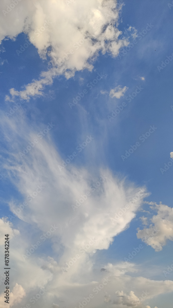 White fluffy clouds moving across a clear blue sky White fluffy clouds moving across a clear blue sky