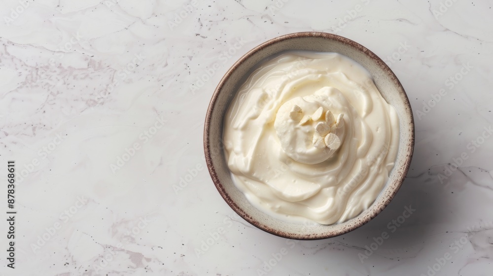 A close-up of a bowl of creamy white yogurt on a light gray marble background. The yogurt is smooth and creamy, and the bowl is simple and rustic. A close-up of a bowl of creamy white yogurt on a light gray marble background. The yogurt is smooth and creamy, and the bowl is simple and rustic.