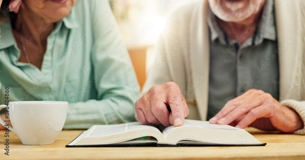 Fototapeta premium Bible, hands and study with senior couple drinking tea at table in apartment together for belief or faith. Book, Jesus or God with man and woman reading in retirement home for Christian religion