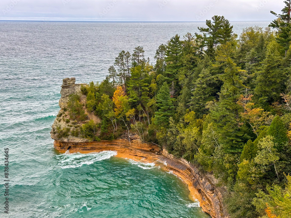 Obraz premium Miner's Castle, a dramatic rock formation in Lake Superior with trees, teal blue water, and an overcast sky