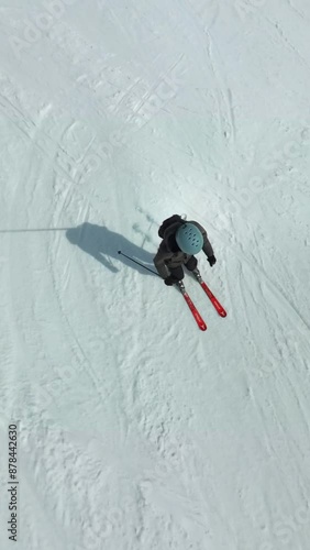 Vertical top shot from above following an amateur  skiing on a ski slope with snow in the austrian Alps photo