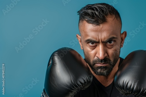 Boxing, guy and fighter practicing, portrait, or challenge on blue studio background. Male boxer or serious athlete with force, face, or energy, training goals, fight, or strong champion © LukaszDesign