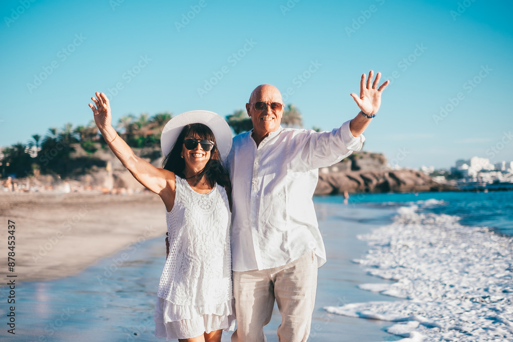 Smiling senior couple enjoying a sunny day at the beach, smiling and embracing each other while dressed in light summer clothes, conveying love, happiness, and companionship Smiling senior couple enjoying a sunny day at the beach, smiling and embracing each other while dressed in light summer clothes, conveying love, happiness, and companionship