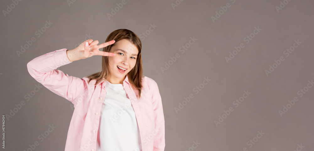 Young caucasian smiling happy friendly woman in stylish casual clothes show victory v-sign gesture isolated on gray background studio portrait People lifestyle concept
