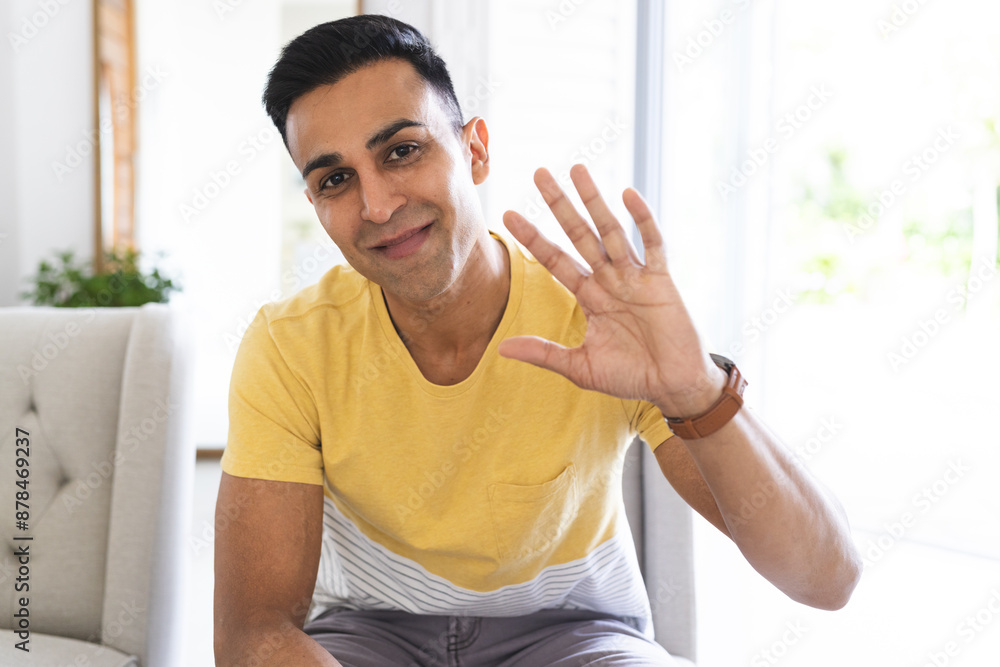 Middle Eastern man greets warmly from a bright home setting during a video call Middle Eastern man greets warmly from a bright home setting during a video call
