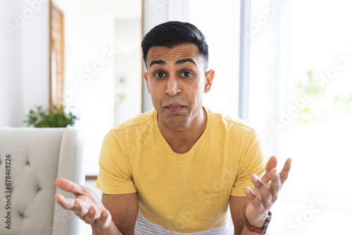 Middle Eastern man gestures in confusion during a video call at home, with copy space