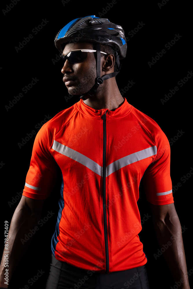 African American cyclist poses confidently on a black background, with copy space African American cyclist poses confidently on a black background, with copy space