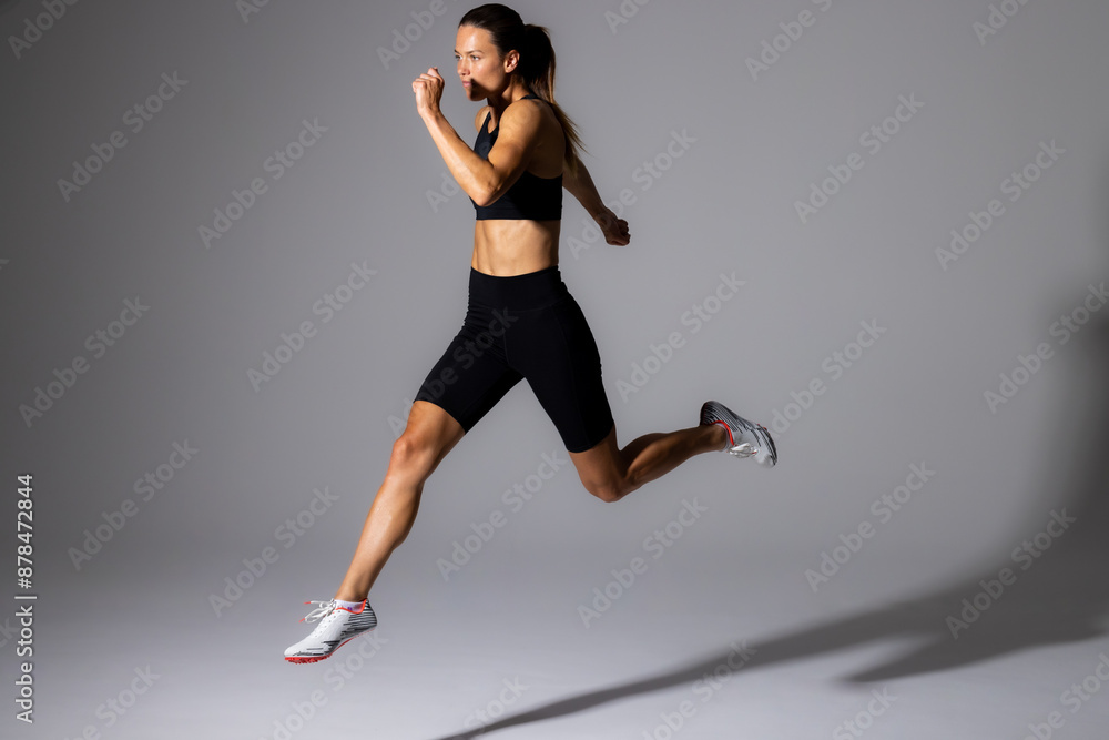 Young Caucasian female athlete in mid-stride during an indoor run on a white background Young Caucasian female athlete in mid-stride during an indoor run on a white background