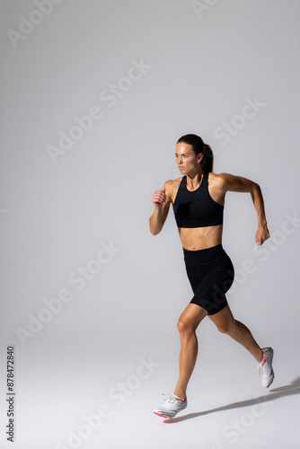 Athletic young Caucasian female athlete sprints in a studio on a white background with copy space