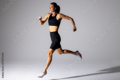 Young Caucasian female athlete sprints in a studio setting, with copy space on a white background