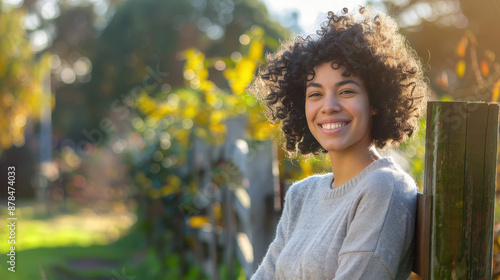 Happy Woman with Curly Hair Smiling Outdoors in Sunny Garden