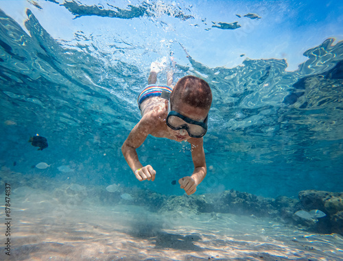 Boy with a mask is diving underwater at sea.