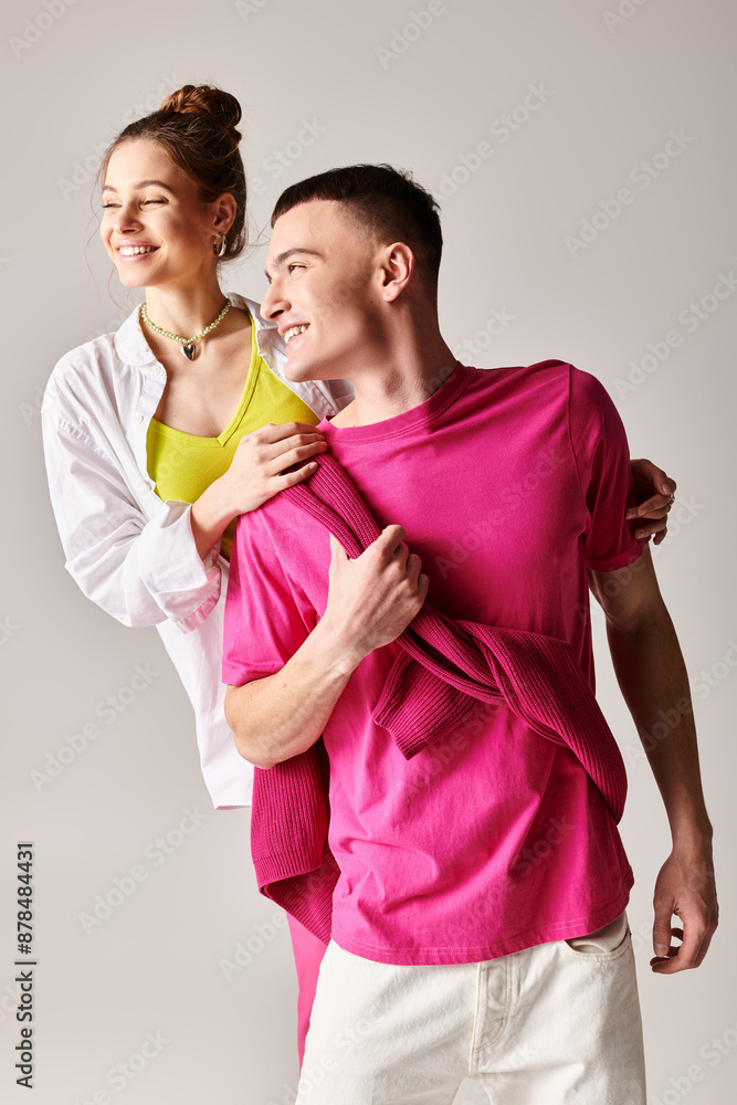 Obraz premium A stylish young couple stands in embrace against a grey studio backdrop, exuding love and connection.