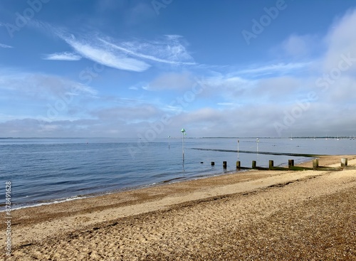 A tranquil view of calm blue waters gently lapping the beach on a bright morning in Chalkwell, Essex, England.  photo