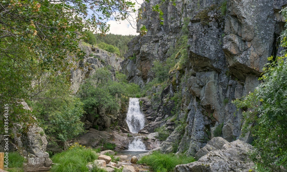 Serene waterfall cascading over rocks into a clear pool surrounded by lush greenery Serene waterfall cascading over rocks into a clear pool surrounded by lush greenery