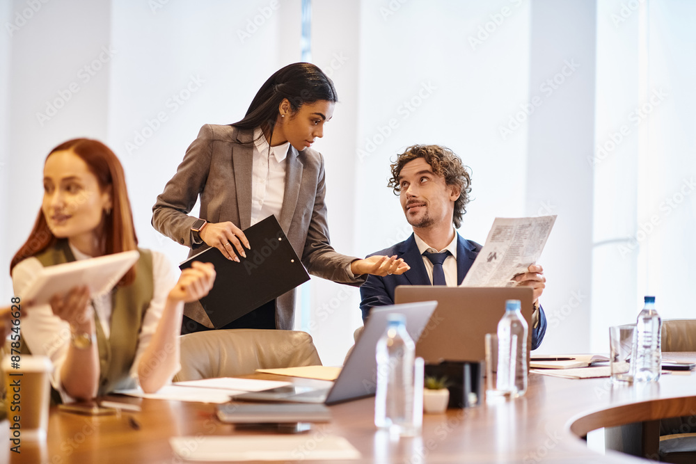 An interracial group of business professionals engaged in a meeting around a conference table. An interracial group of business professionals engaged in a meeting around a conference table.