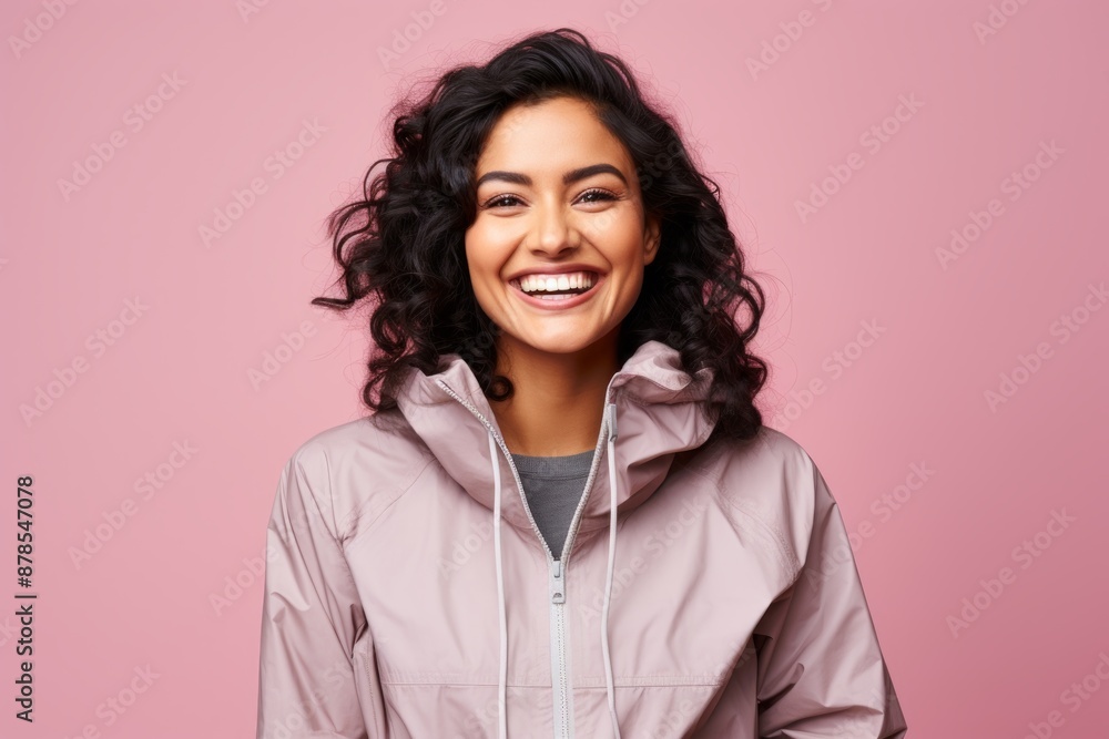 Portrait of a grinning indian woman in her 20s wearing a functional windbreaker isolated in pastel or soft colors background Portrait of a grinning indian woman in her 20s wearing a functional windbreaker isolated in pastel or soft colors background