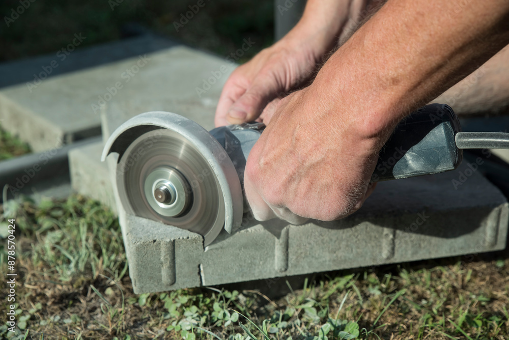 osoba tnąca szlifierką element z betonu