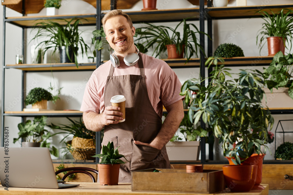 A man in an apron holding a cup of coffee. He is in a plant shop, reflecting a small business owner taking a break. A man in an apron holding a cup of coffee. He is in a plant shop, reflecting a small business owner taking a break.