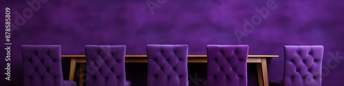 Purple velvet chairs and a wooden table against a purple wall, creating a luxurious and elegant atmosphere. 

