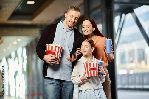A joyful family at the cinema, holding popcorn bags together.