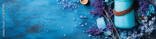 Blue and purple flowers, sea salt, and a blue jar on a blue background, perfect for spa, beauty and wellness branding. 
