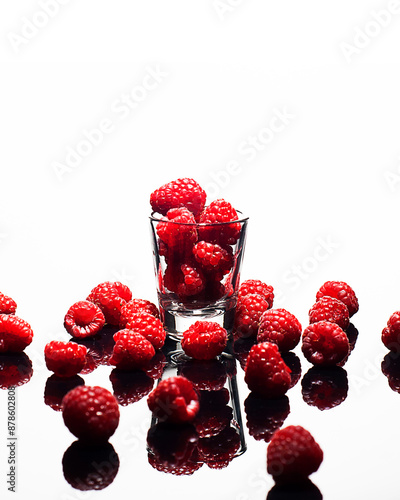 Shot Glass Full of Raspberries Overflowing on White Background