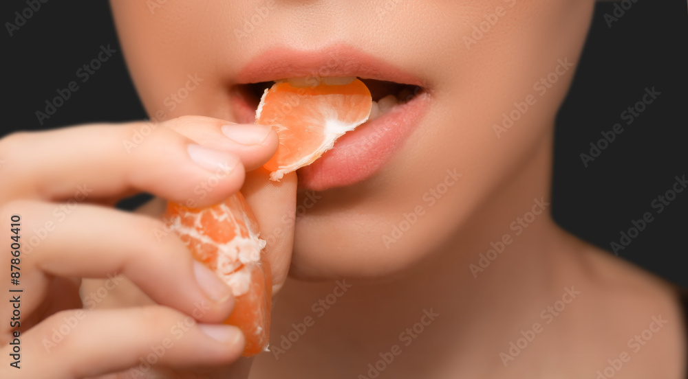 Woman Eating an Orange Slice. Close-up of a woman about to eat a slice of orange against a black background. Woman Eating an Orange Slice. Close-up of a woman about to eat a slice of orange against a black background.