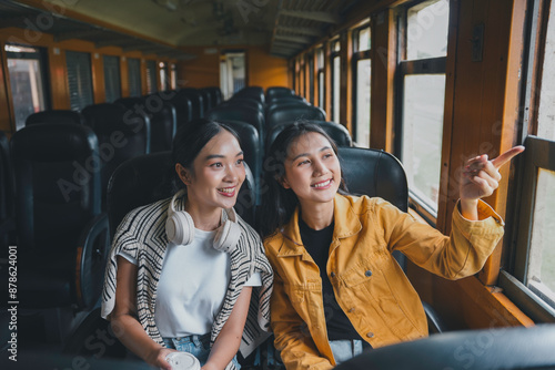 Two friends savor the sights on their train ride, sharing a moment of joy as they travel to a new destination © amnaj