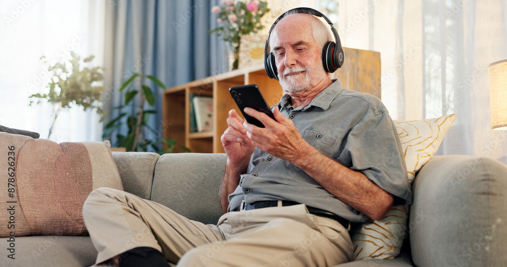 Phone, headphones and senior man on sofa for streaming music with retirement, jazz playlist and relax in home. Elderly person, mobile and listening to podcast for entertainment, online audio or radio Phone, headphones and senior man on sofa for streaming music with retirement, jazz playlist and relax in home. Elderly person, mobile and listening to podcast for entertainment, online audio or radio