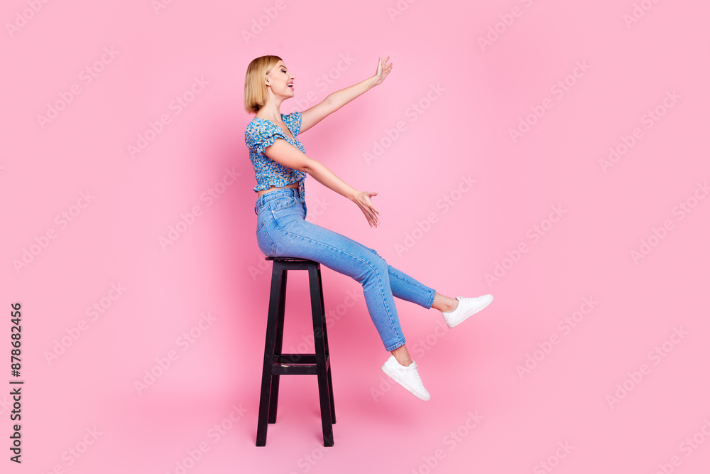 Full length photo of charming excited woman wear blue blouse sitting stool catching empty space isolated pink color background Full length photo of charming excited woman wear blue blouse sitting stool catching empty space isolated pink color background
