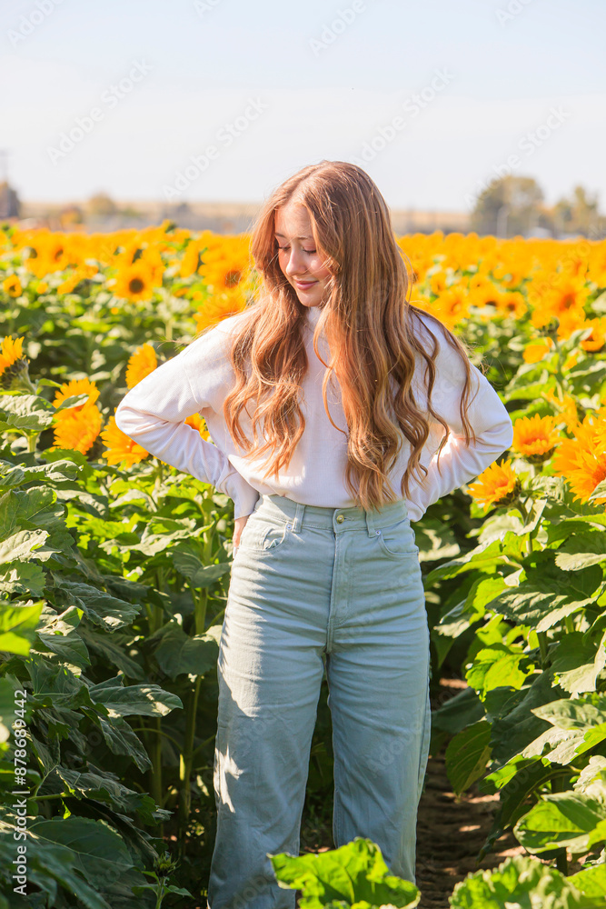 Happy blonde teenage girl in sunflower field.