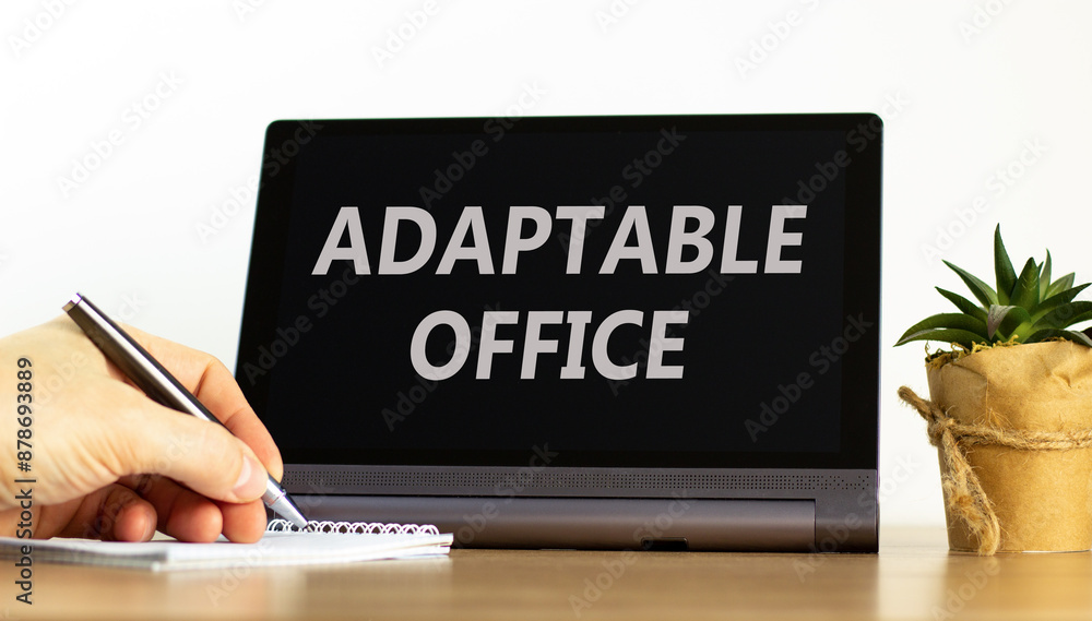 Adaptable office symbol. Concept words Adaptable office on beautiful black pad. Beautiful white background. Businessman hand. Business Adaptable office concept. Copy space. Adaptable office symbol. Concept words Adaptable office on beautiful black pad. Beautiful white background. Businessman hand. Business Adaptable office concept. Copy space.