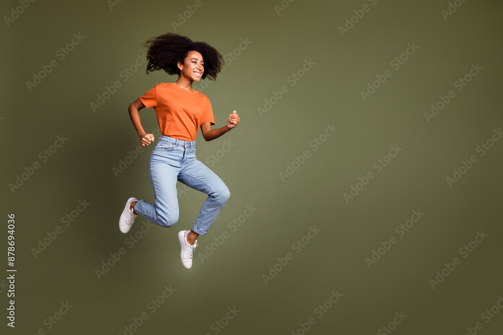 Full length photo of shiny attractive lady dressed orange outfit jumping high running empty space isolated khaki color background Full length photo of shiny attractive lady dressed orange outfit jumping high running empty space isolated khaki color background