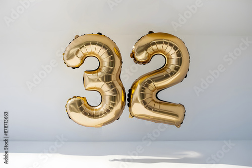Golden Foil Balloons Forming the Number 32 on a Light Background