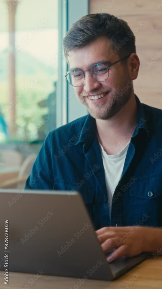 Vertical Screen: Happy Caucasian Freelancer Smiling While Looking at the Laptop Screen in a Coffee Shop. Young Web Developer Enjoying Online Work. Concept of Digital Nomad, Remote Job Vertical Screen: Happy Caucasian Freelancer Smiling While Looking at the Laptop Screen in a Coffee Shop. Young Web Developer Enjoying Online Work. Concept of Digital Nomad, Remote Job