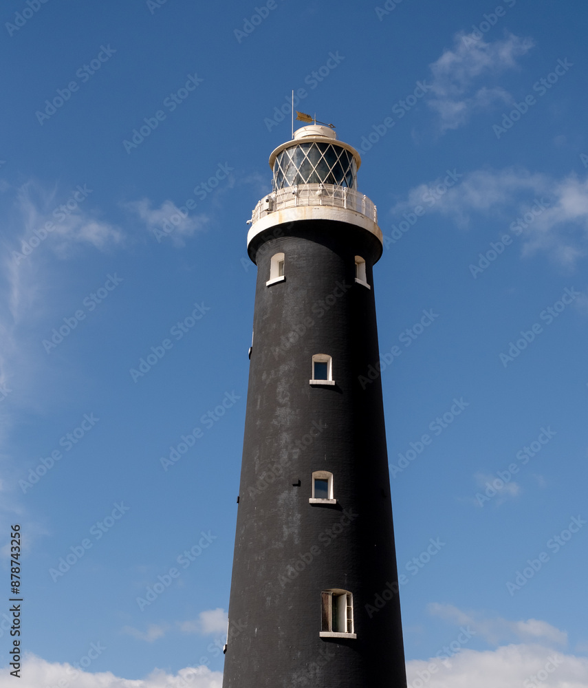 A black lighthouse captured against a bright blue sky