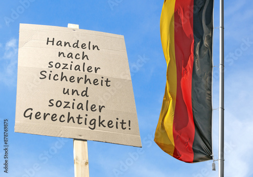Schild mit der Devise: Handeln nach sozialer Sicherheit und sozialer Gerechtigkeit mit deutsche Nationalflagge photo