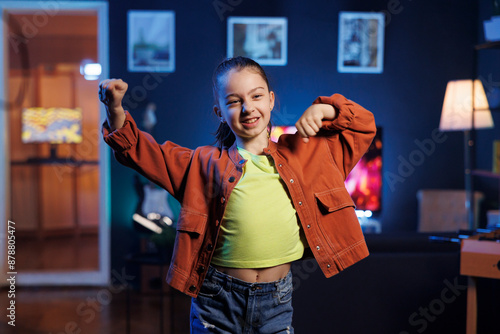 Pretty little girl dancing and singing while shooting video for social media networks in home interior background. Child entertaining audiences with professional choreography