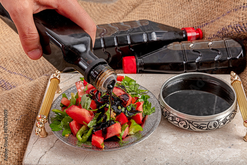 Pomegranate syrup and salad. A girl pouring pomegranate syrup on seasonal salad. photo