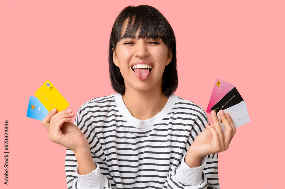 Beautiful young woman with many credit cards showing tongue on pink background Beautiful young woman with many credit cards showing tongue on pink background