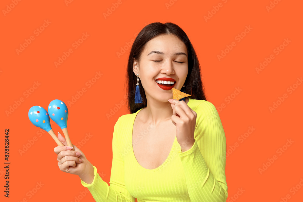 Portrait of young woman with maracas and tortilla chip on orange background. National Tortilla Chip Day celebration Portrait of young woman with maracas and tortilla chip on orange background. National Tortilla Chip Day celebration