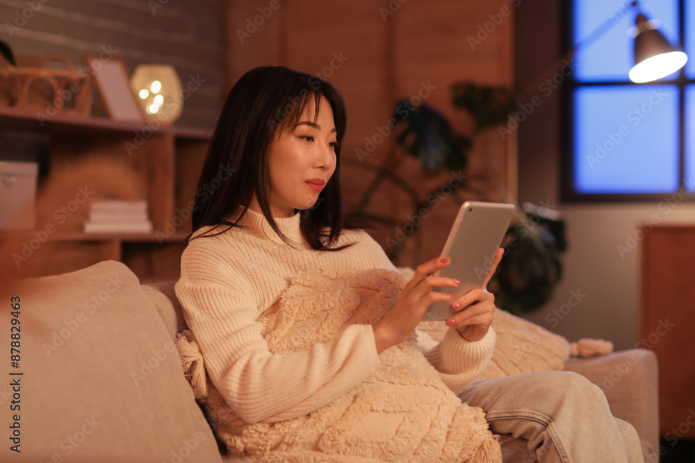 Young Asian woman relaxing on sofa with tablet in living room Young Asian woman relaxing on sofa with tablet in living room