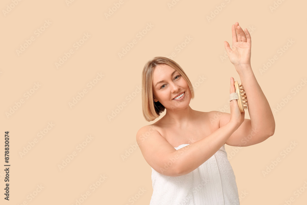 Beautiful young woman massaging her arm with arm massage brush on beige background Beautiful young woman massaging her arm with arm massage brush on beige background