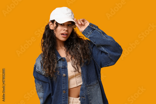 Photography Young African-American woman in baseball cap and stylish clothes on yellow backg