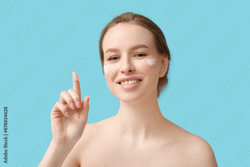 Young woman with cream pointing at something on blue background Young woman with cream pointing at something on blue background
