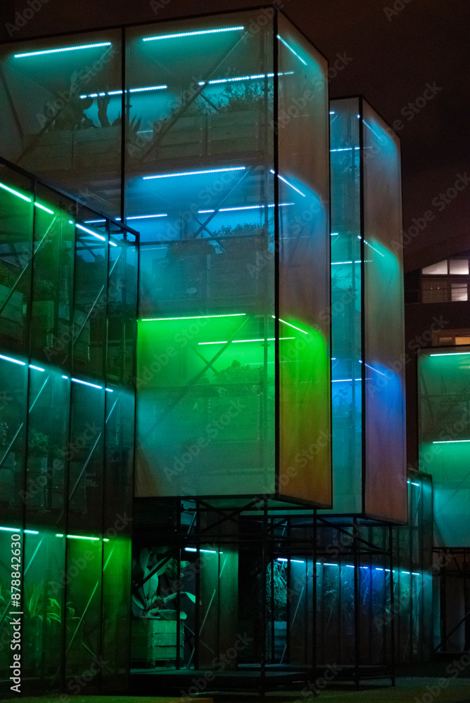 Obraz premium A futuristic glass greenhouse with plants, illuminated by neon lights, creating an enchanting and modern scene.