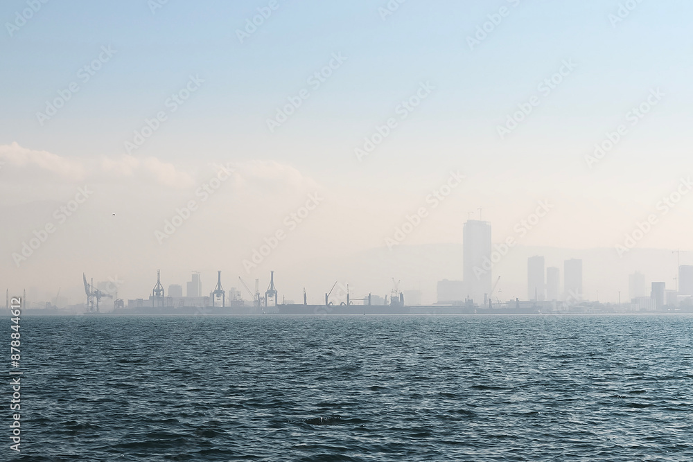 A serene view of the port in Izmir Bay enveloped in fog, creating a mysterious and tranquil atmosphere. A serene view of the port in Izmir Bay enveloped in fog, creating a mysterious and tranquil atmosphere.